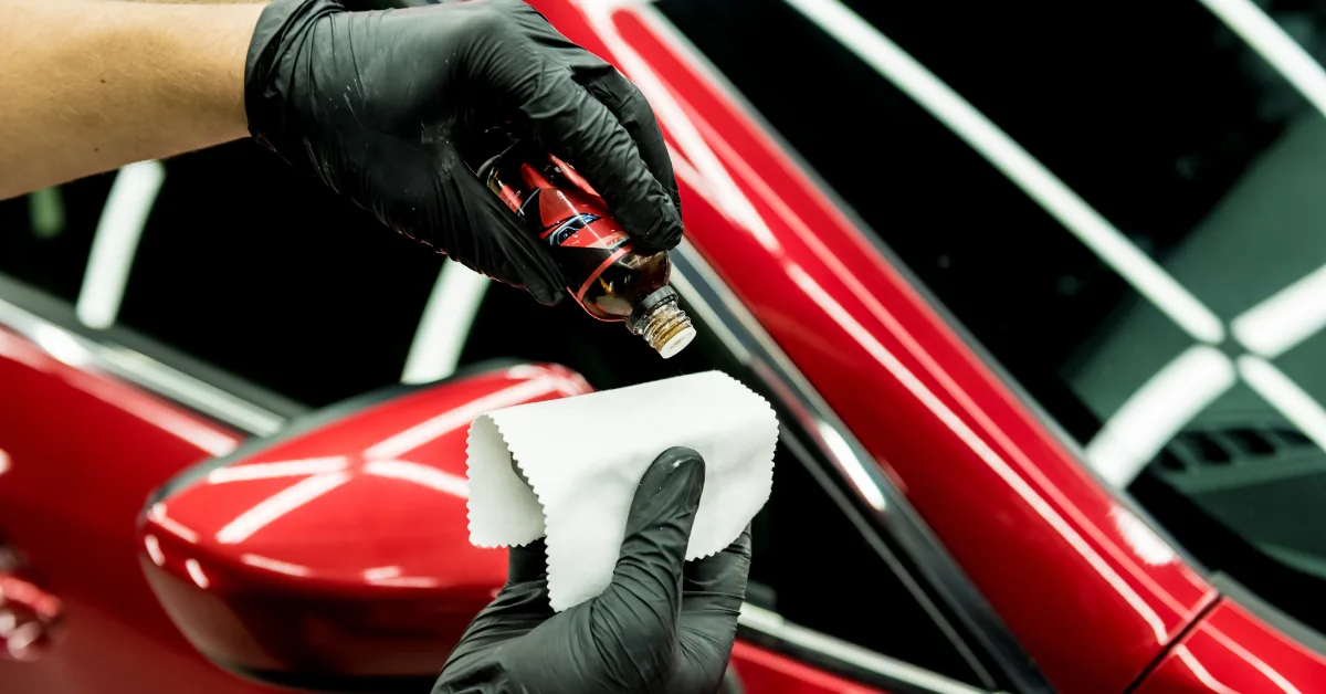 Gloved hand levelling ceramic coating on a red car body panel