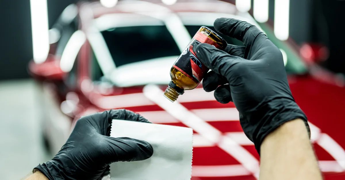 Gloved installer using a squeegee to set protection film on a red and white car